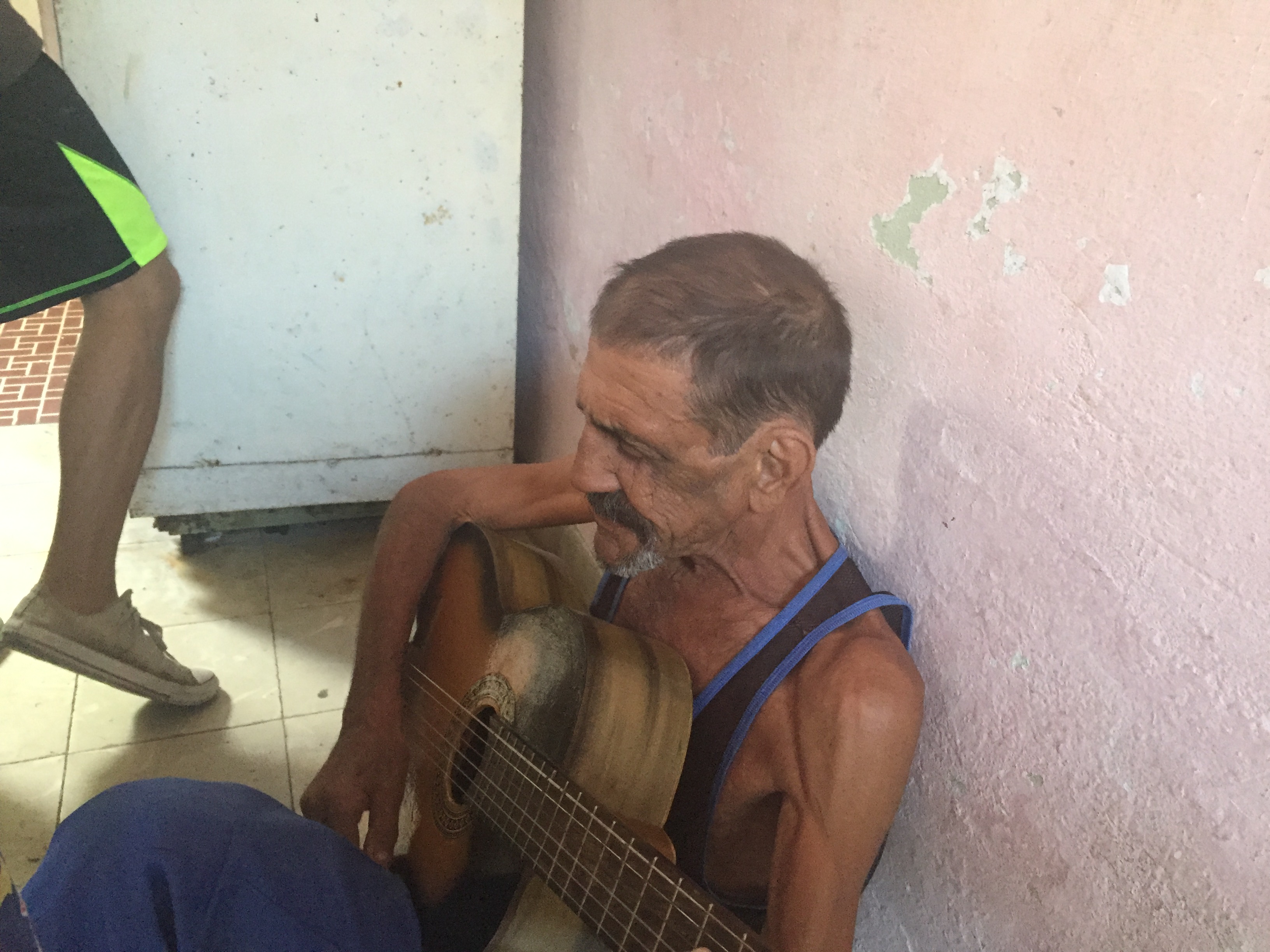 Papi wearing a Che Guevara beret, guitar slung over his shoulder, singing among family.